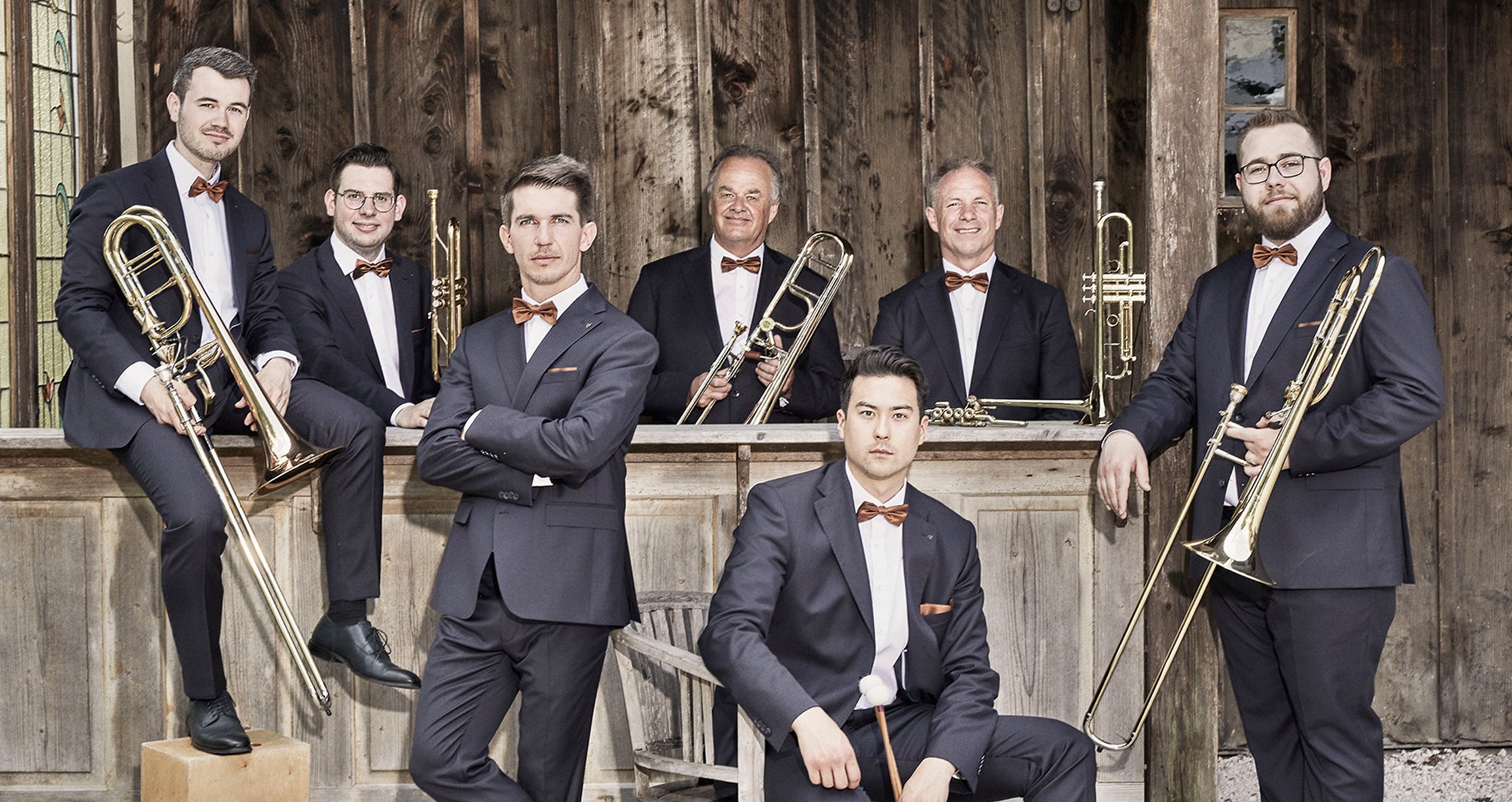 Eine Gruppe von Männern in Anzügen posiert für ein Foto mit Musikinstrumenten in der Hand.