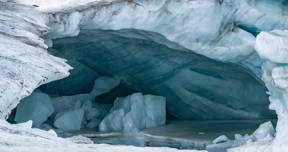 Eine große Eishöhle mit einem kleinen Loch, das Licht und Schatten in die eisige Umgebung bringt.