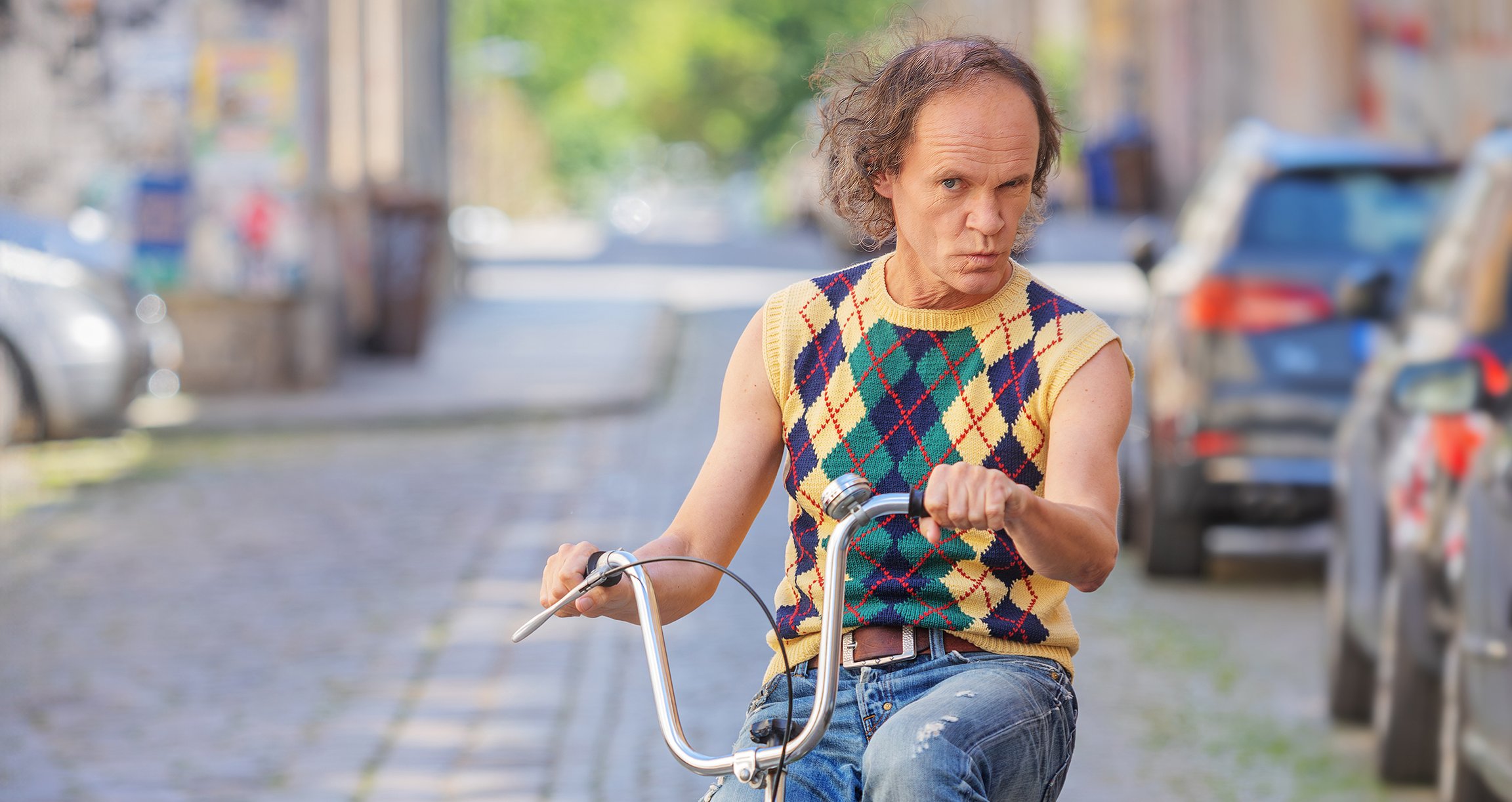 Olaf Schubert auf einem Fahrrad, während er in die Kamera schaut