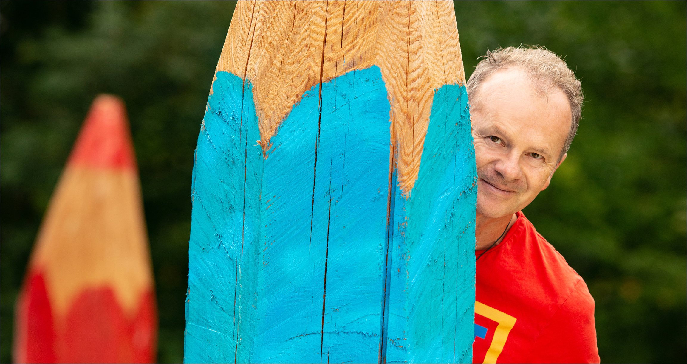 Ein Mann hält einen großen, blauen Holzstift in der Hand