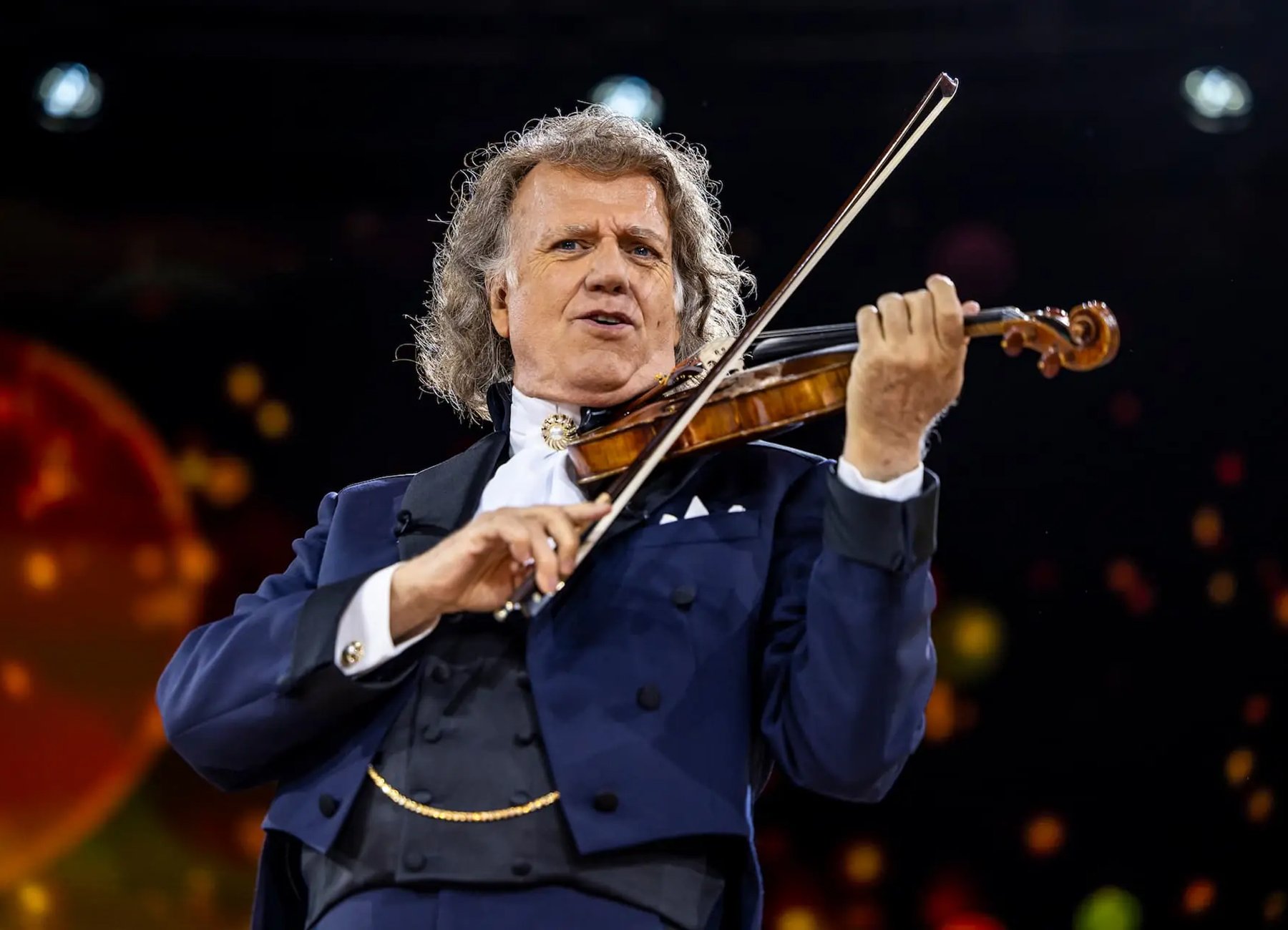 André Rieu während er in einem blauem Anzug Violine spielt