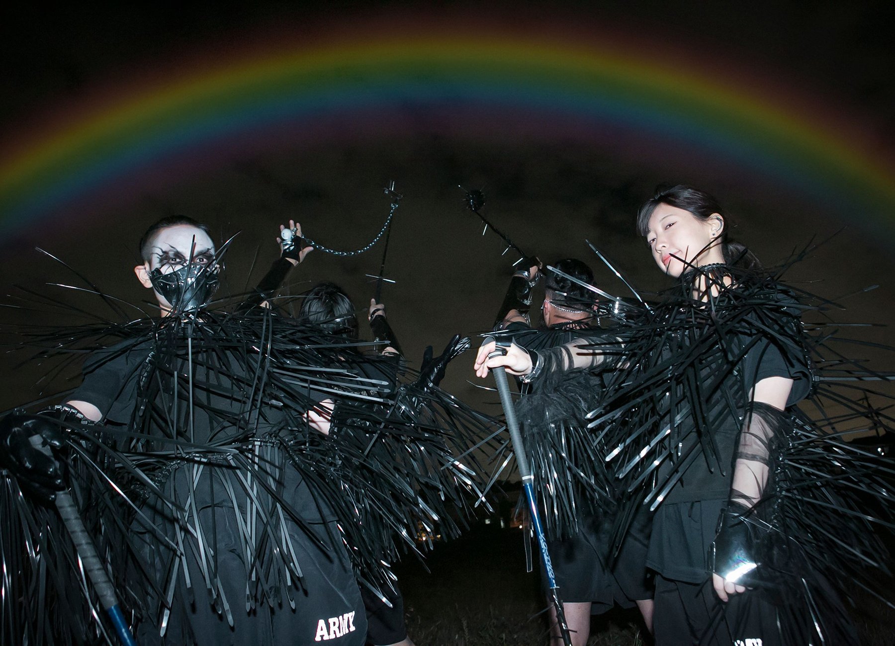 Violent Magic Orchestra stehen mit schwarzen Kostümen unter einem Regenbogen