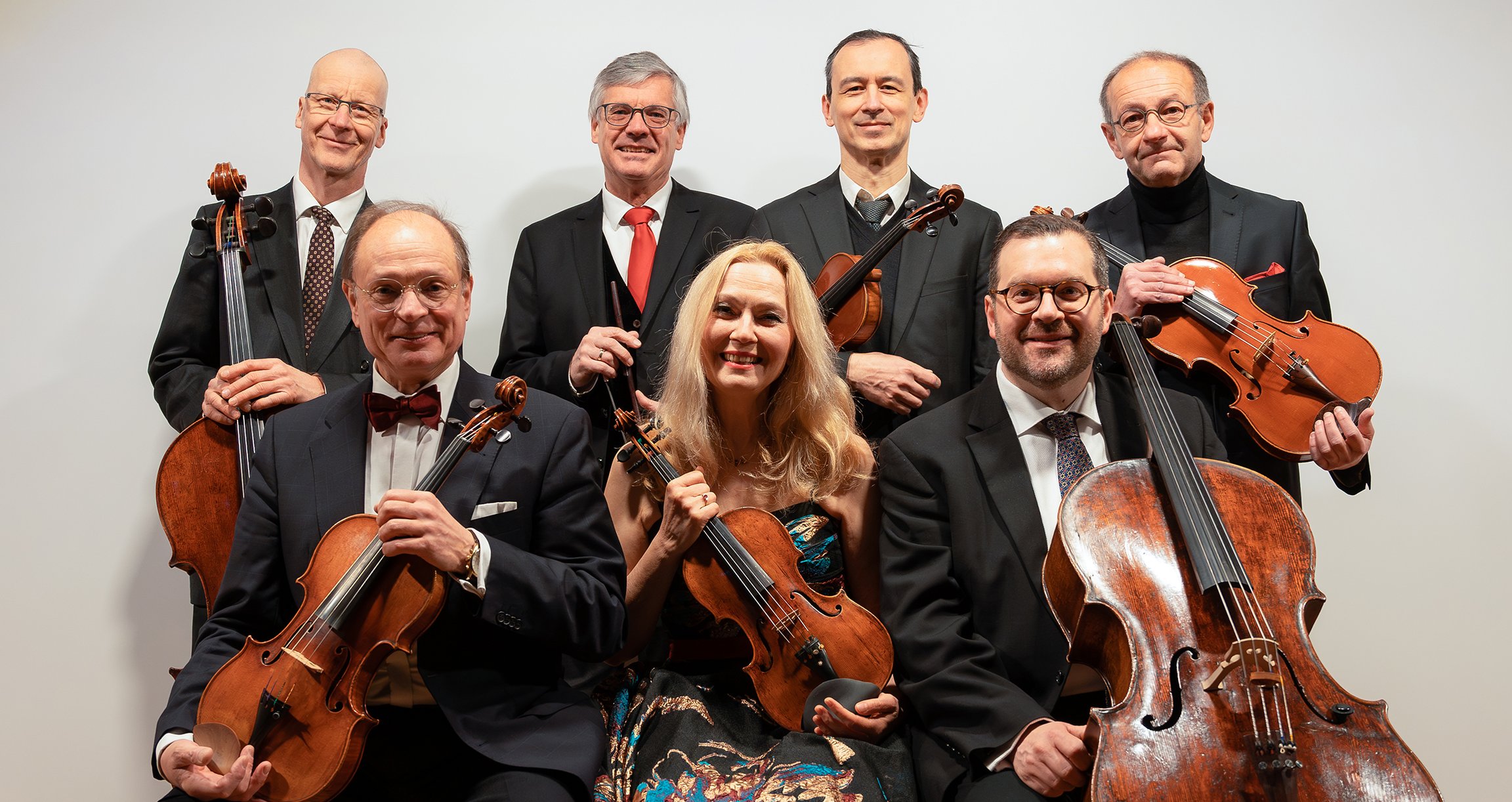 Ein Gruppenbild bestehend aus sieben Personen, welche alle Streichinstrumente in der Hand halten. 